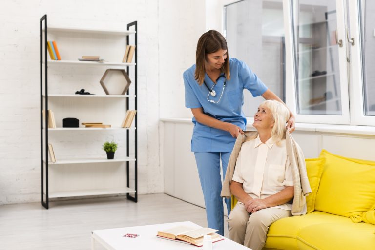 O asistentă medicală oferă sprijin unei paciente în vârstă la domiciliu.